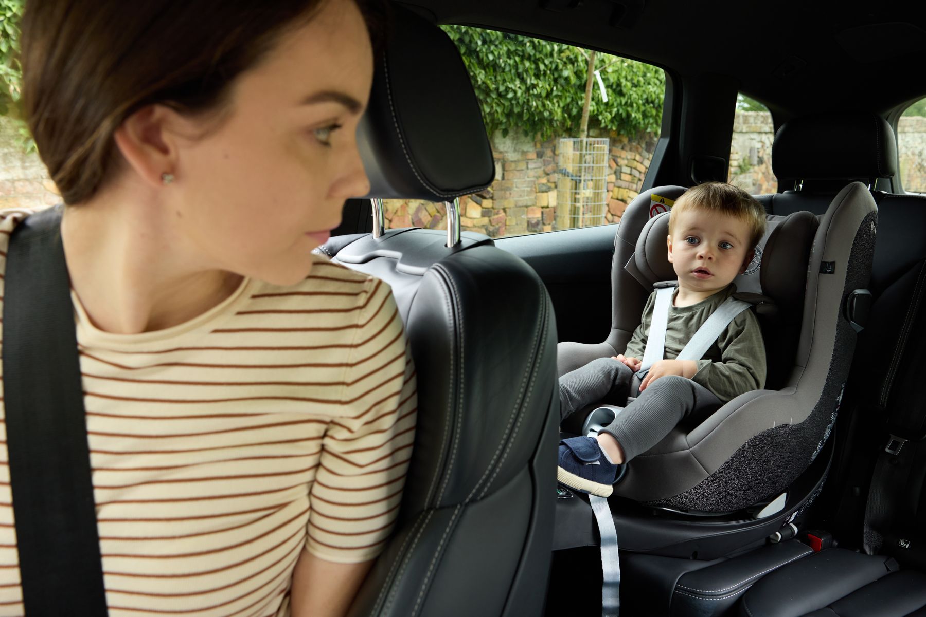 A mum turning to check on her toddler in his car seat