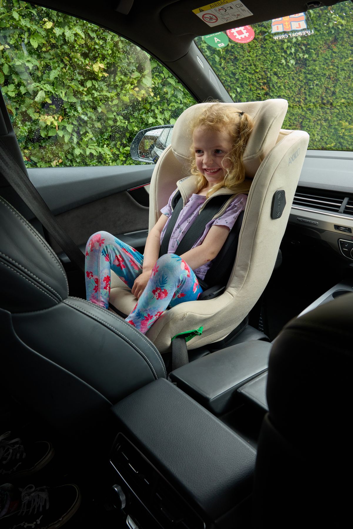 A smiling girl sitting in a forward-facing car seat
