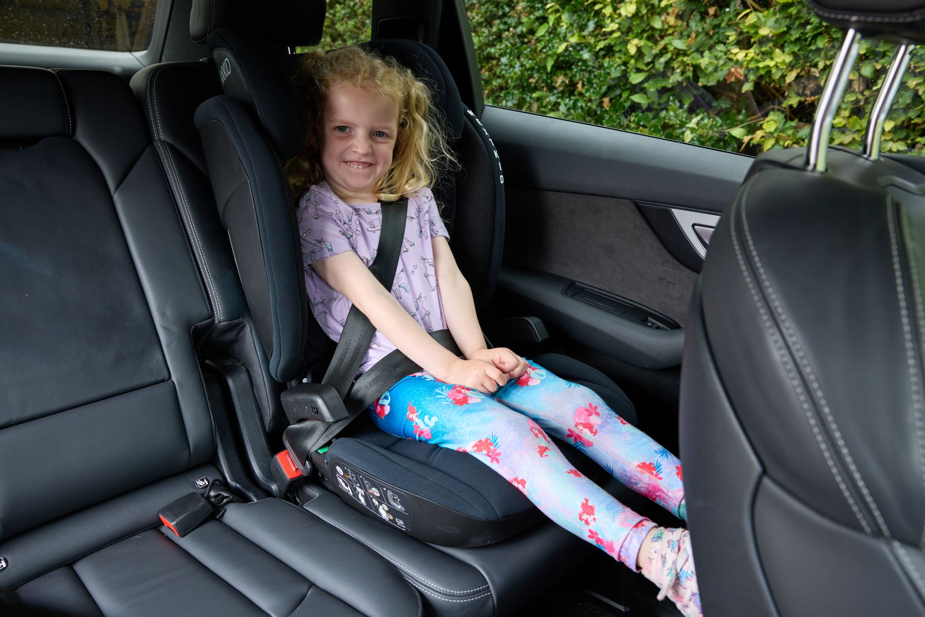A girl sitting on a booster cushion with the seat belt fitted